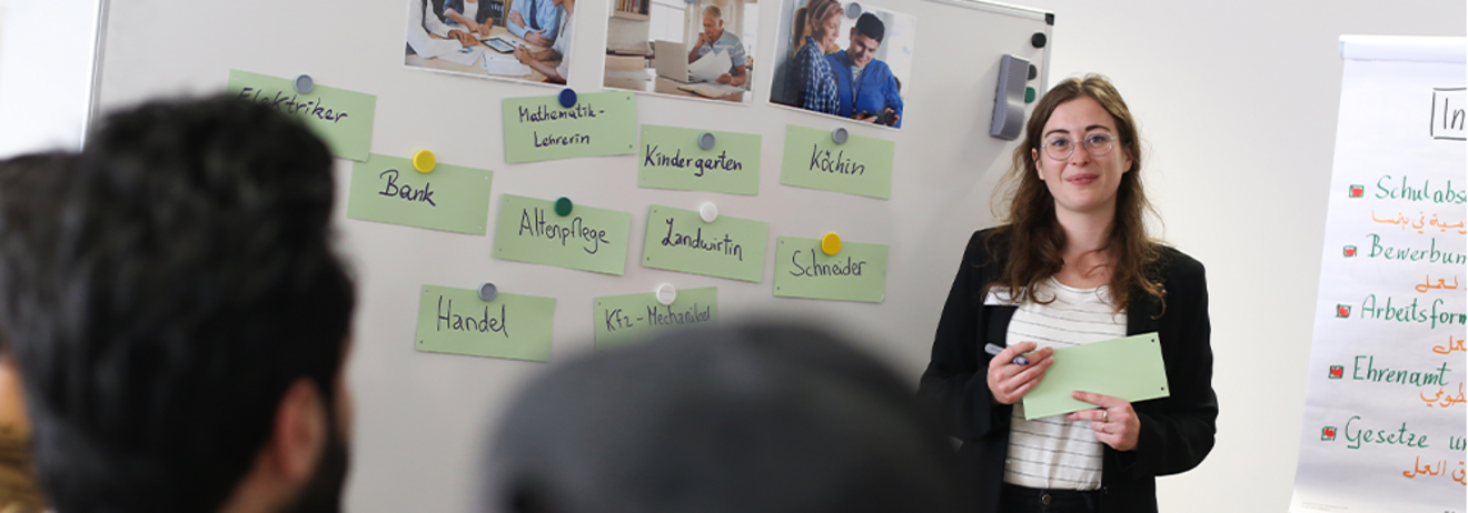 Eine Referentin präsentiert verschiedene Berufsbezeichnungen an einer Tafel während einer Schulung.