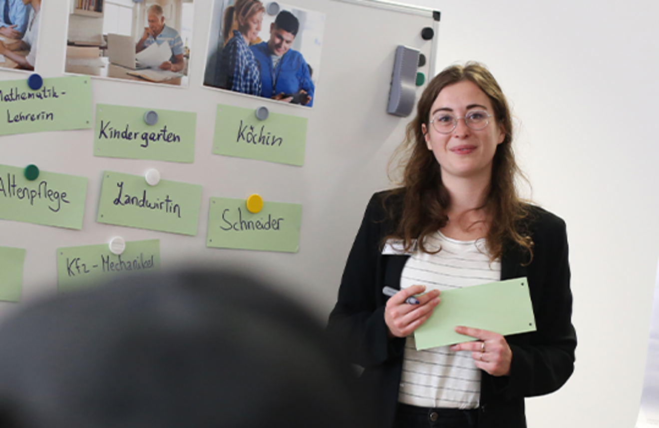Eine Referentin präsentiert verschiedene Berufsbezeichnungen an einer Tafel während einer Schulung.